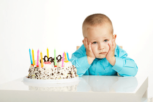 Bé trai chống cằm buồn rầu trong ngày sinh nhật