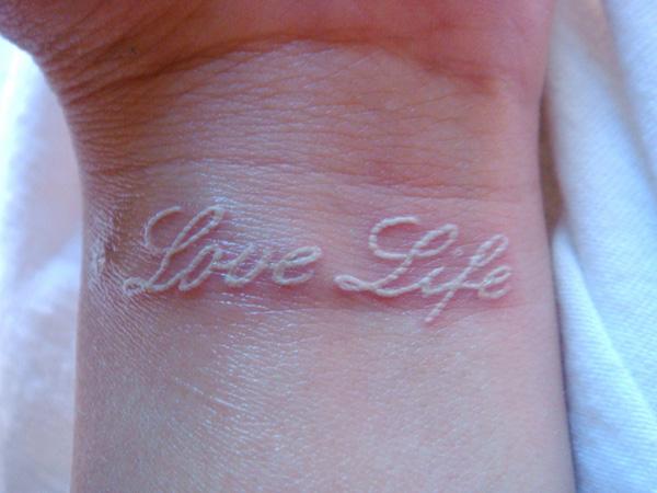 Ảnh chữ Love Life màu trắng xăm trên cổ tay